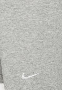 Tela de sudadera gris con una textura sutil, con un logo de Nike blanco bordado en la parte inferior delantera.