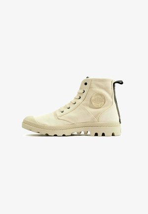 Botte montante beige en toile avec une semelle en caoutchouc et des accents texturés. Dotée d'un patch logo rond et d'une languette sur le talon.