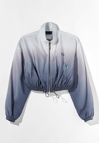 Giacca cropped con una transizione di colore gradiente dal bianco al grigio scuro, tessuto morbido, chiusura con zip, orlo e polsini elasticizzati, e tasche laterali.