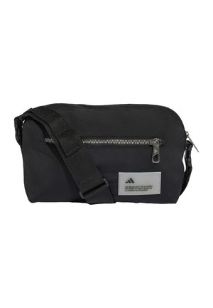 Zwarte crossbodytas met verstelbare band, voorvak met rits en stoffen Adidas-logo patch met tekst in drie talen.