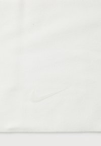 Biała tkanina o miękkiej teksturze z subtelnym, wytłoczonym logo Nike w tym samym kolorze, umieszczonym w dolnym prawym rogu.