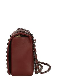 Borsa a mano in pelle rossa con tracolla a catena, forma rettangolare e borchie argentate lungo i lati. Texture liscia e design minimalista.