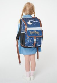 Modrý batoh s motivem Harryho Pottera s hnědými akcenty, zobrazujícími obrázky a vzory z Havraspáru, nastavitelné popruhy a přední sponu.