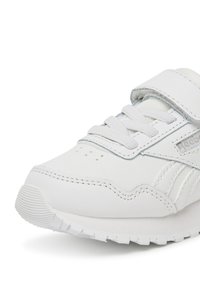 Valge nahast ja võrgust toss, millel on polsterdatud pahkluuosa, reguleeritav takjakinnitus ja tekstuuriga kummist tallad.