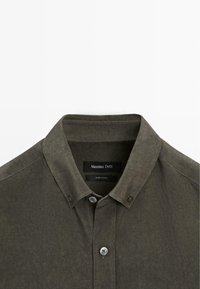 Olivgrünes Hemd mit Knöpfen, einem Kragen und vorderen Knöpfen, Nahaufnahme des oberen Brust- und Halsbereichs.