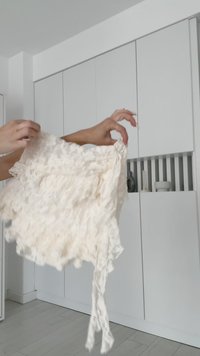 Fustă din dantelă crem, ridicată, cu un design texturat și volănat, având un tiv desfăcut. Material ușor, împodobit cu modele intricate.