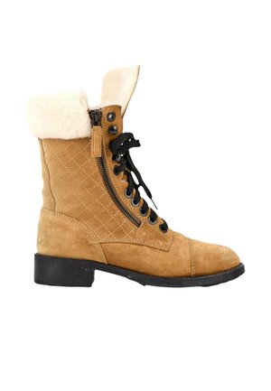 Bottine en daim beige à lacets noirs, fermeture éclair latérale, motif matelassé, revers en peau lainée crème et semelle noire à petit talon.
