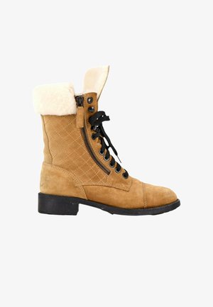 Bottine en daim beige à lacets noirs, fermeture éclair latérale, motif matelassé, revers en peau lainée crème et semelle noire à petit talon.
