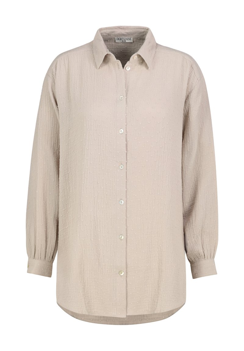 Hellbeiges Hemd zum Knöpfen mit strukturiertem Muster, langen Ärmeln mit gerafften Bündchen und einem abgerundeten Saum, versehen mit kleinen, runden Knöpfen.