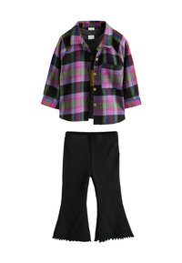 Chemise écossaise multicolore avec des motifs noirs, violets et verts, associée à un pantalon noir évasé avec un ourlet volé.