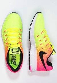 Běžecké boty Nike s jasným neonově žlutým a růžovým gradientním designem, síťovinovým svrškem, černými akcenty a lehkou bílou podrážkou.