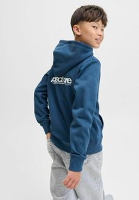 Felpa blu navy con tasca a marsupio, polsini a costine e logo bianco sul retro. Realizzata in tessuto morbido e testurizzato.