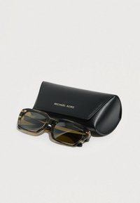 Ορθογώνια γυαλιά ηλίου με θαλασσινό σχέδιο και σκούρους φακούς τοποθετημένα δίπλα σε μια μαύρη δερμάτινη θήκη Michael Kors σε λευκή επιφάνεια.