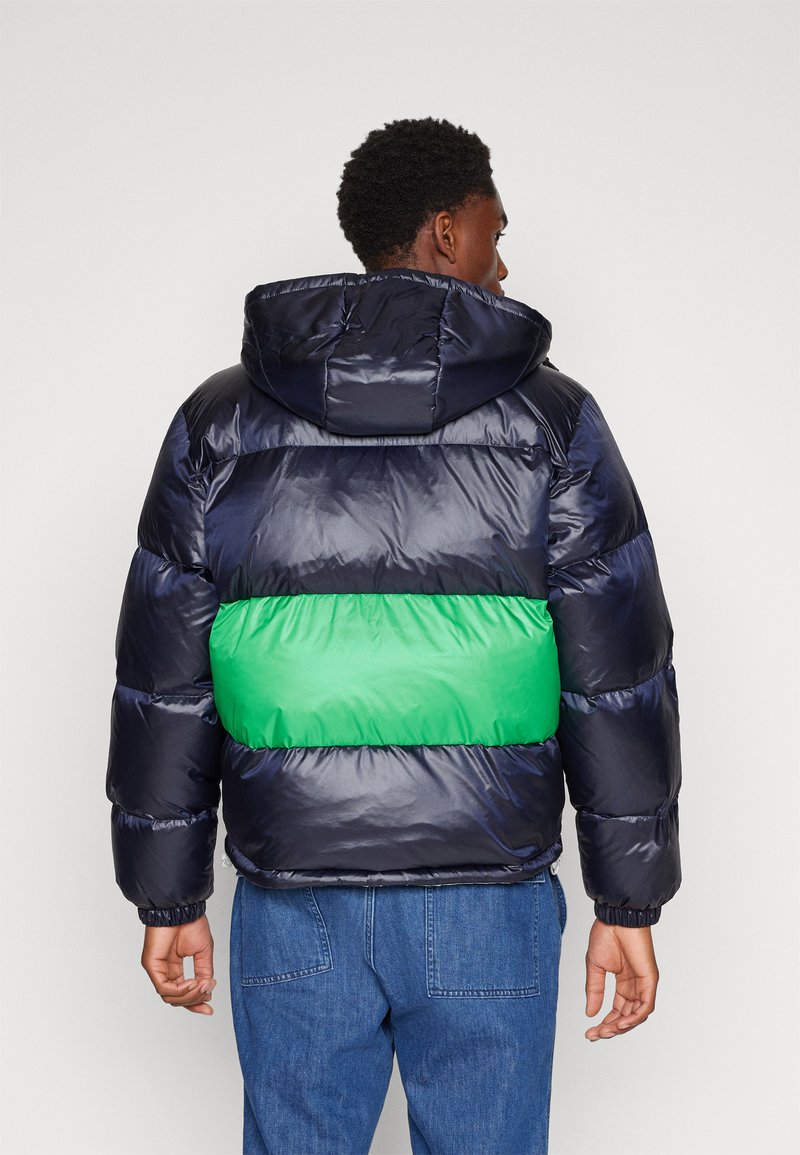 Daunenjacke mit einem marineblauen und grünen Farbblockdesign, Kapuze, gerippten Bündchen und glatter Textur. Hat eine kastige Form für Wärme.
