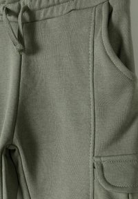Olijfgroene katoenen joggers met een elastische tailleband, zijzakken en een textuurstof met zichtbare stikseldetails.