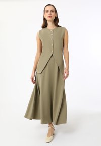 Robe sans manches vert olive avec un corsage ajusté, une jupe évasée et six boutons décoratifs à l'avant ; texture lisse, design longueur cheville.