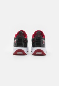 Schwarze Lackleder- und Mesh-Sneaker mit roten Akzenten, weißen Sohlen und einer strukturierten Gummisohle. Mit einem auffälligen Logo an der Ferse.