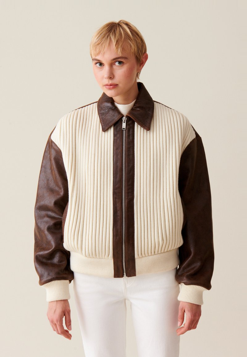Braune und cremefarbene Bomberjacke mit gerippter Textur, Lederärmeln, Reißverschluss und Strickbündchen am Kragen, Saum und an den Ärmeln.