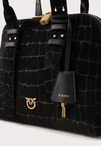 Μαύρη τσάντα χειρός σε σχέδιο κροκοδείλου με χρυσό φερμουάρ, έμβλημα πουλιού και δερμάτινη ετικέτα με ανάγλυφο "PINKO" και κρεμαστά χρυσά κλειδιά.