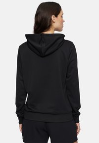 Svart hoodie i ett mjukt, glansigt tyg med justerbar huva, ribbad muddar och fåll. Har en avslappnad passform och bakvy.