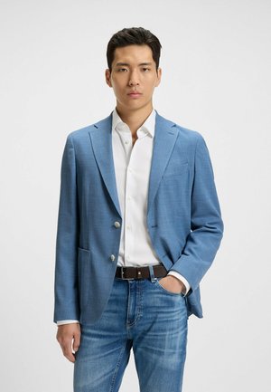 Light blue, textured blazer with two buttons, front pockets, and a notch lapel, worn over a white shirt and blue jeans. Brown belt accent.