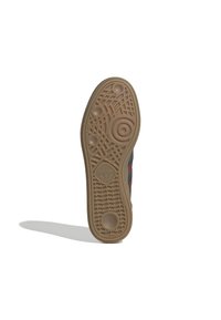 Sole hnědé tenisky Adidas s kruhovými a geometrickými vzory podrážky a logem Adidas ve středu.