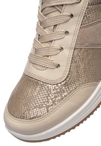 Béžový a kovový teniskový špička se vzorem hadí kůže se tkanými tkaničkami a bílou gumovou podrážkou, zobrazující detailní texturu a šití.