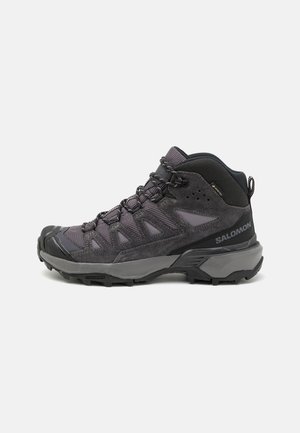 Bota de senderismo de corte medio en gris oscuro con materiales sintéticos y de malla, suela resistente, puntera reforzada y cierre de cordones para un ajuste seguro.