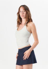 Light gray, fitted tank top in a soft fabric, paired with a navy blue mini skirt, featuring a smooth texture and a button accent.