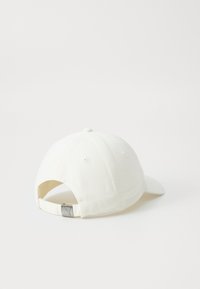 Boné de baseball branco de algodão com aba curva e fivela ajustável de metal prateado na parte de trás. Tecido texturizado com pequenos orifícios de ventilação.