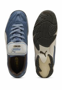 Sapatilha Puma King azul e branca com atacadores, logótipos da marca visíveis na língua e na sola, exibida em vistas superior e inferior.