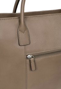 Nabijfoto van een beige leren schoudertas met een ritsvak, een gladde textuur, nette stiksels en stevige handgrepen.