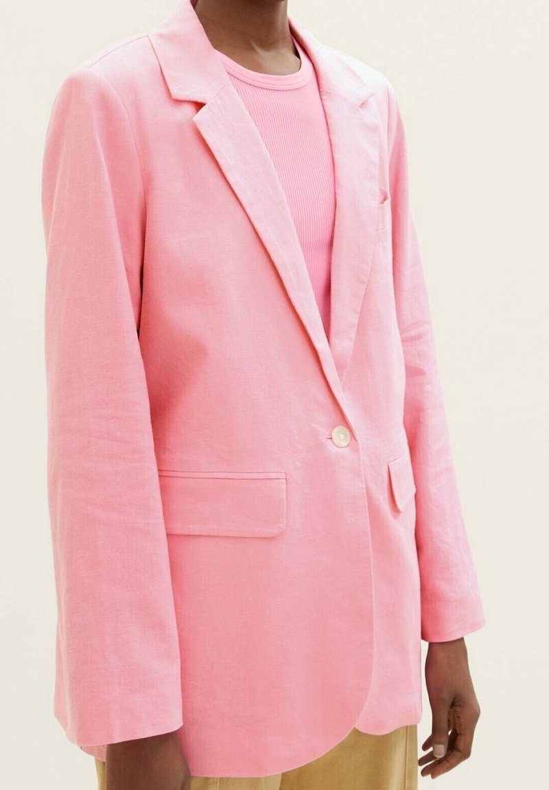 Růžový lněný blazer s volným střihem, jednořadým zapínáním na knoflík, klopami a předními kapsami, v kombinaci s odpovídajícím žebrovaným topem.