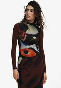 Rochia are caracteristici o croială mulată, cu un design multicolor, guler înalt și mâneci lungi. Materialul îmbină elemente netede și texturate, având modele abstracte.