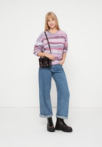 Multicolored knitted sweater with pink and purple patterns, paired with light blue wide-leg jeans and black lace-up ankle boots.