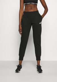 Pantalones de chándal negros con puños elásticos, bolsillos laterales y detalle de logotipo en blanco. Tejido suave con un corte relajado para mayor comodidad y movilidad.