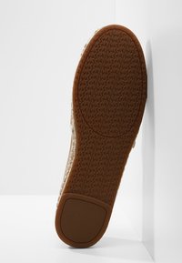 Suela de zapato con superficie de goma texturizada, con un patrón de espina de pescado. El color es marrón con un acento en tono beige alrededor del área del talón.