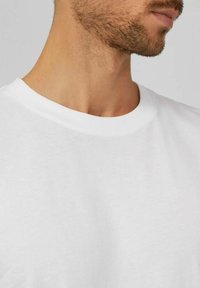 Camiseta de algodón blanca con cuello redondo y mangas cortas, que presenta una textura suave y un ajuste clásico.