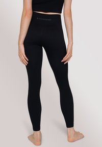 Leggings neri realizzati in materiale elastico con un’alta vita. Presentano un logo sul retro e una vestibilità aderente lungo le gambe.