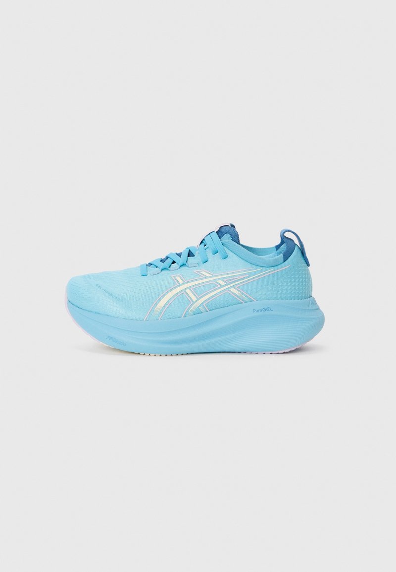 Chaussure de course athlétique bleu clair avec semelle épaisse, lacets et bandes blanches avec logo sur le côté sur un fond gris clair.
