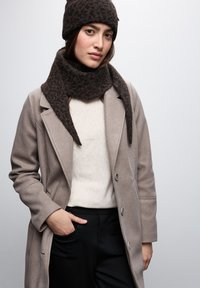 Beanie e sciarpa a maglia con motivo marrone abbinati a un maglione color crema chiaro e un cappotto grigio, con design su misura e due tasche frontali.