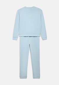 Světlý modrý svetr a odpovídající kalhoty z měkké látky; mají žebrované manžety a pas; jednoduchý design bez viditelných log nebo vzorů.