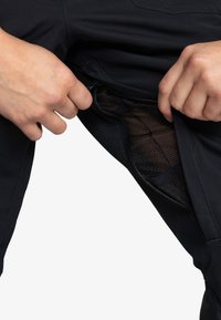 Zwarte broek met een ritszak en een gaasvoering. De stof lijkt glad en rekbaar, wat de flexibiliteit en het comfort vergroot.
