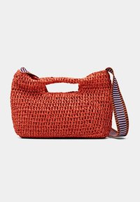 Sac tissé rouge avec une surface texturée, une poignée supérieure et une bandoulière rayée réglable. Forme compacte, adaptée à un usage décontracté.