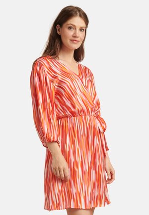 Korte mouw wikkeljurk in tinten van rood, roze en oranje met een gestreept patroon, voorzien van een strikomtrek en een v-hals. Zijdeachtige textuur.