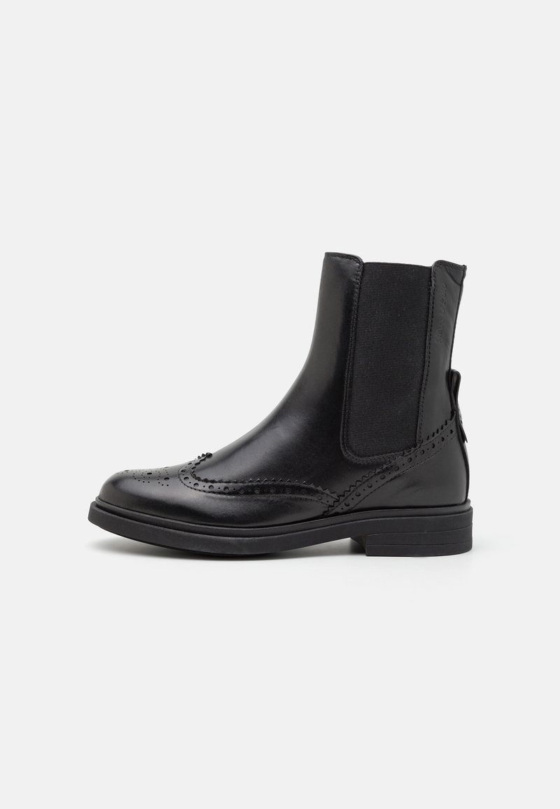 Bottette en cuir noir avec panneaux latéraux élastiques, détails brogue, talon bas et bout arrondi.
