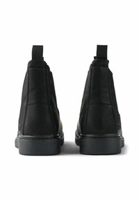 Botas de cuero negras hasta el tobillo con un acabado texturizado, que cuentan con una lengüeta y suelas de goma, vistas desde la parte de atrás.