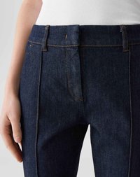 Un jean en denim foncé avec une taille haute, ornée de coutures orange et d'une seule poche avant, au design ajusté et à la texture lisse.