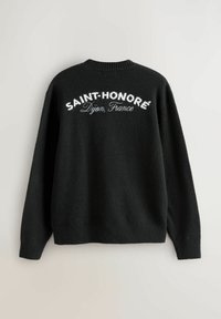 Sort langærmet sweater med hvid tekst "SAINT-HONORÉ" og "Dijon, Frankrig" på ryggen, ribbede cuffs og kant, ensfarvet baggrund.