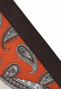 Orange fabric featuring white paisley patterns, bordered by a dark brown edge. Smooth texture with intricate detailing in the design.